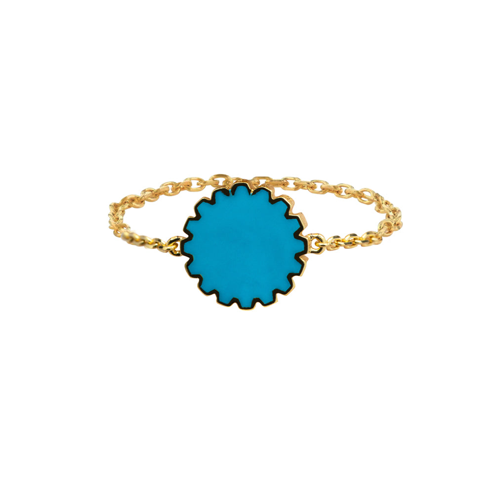 Ring with a blue circular charm and gold chain on a white background