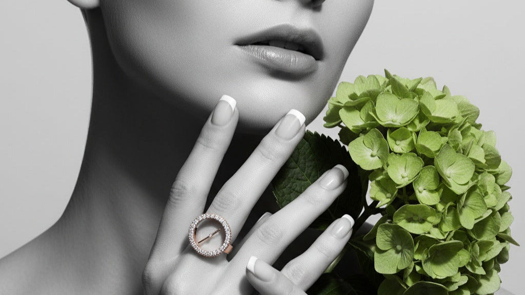 Woman's hand with a ring holding a green flower, with a black and white background
