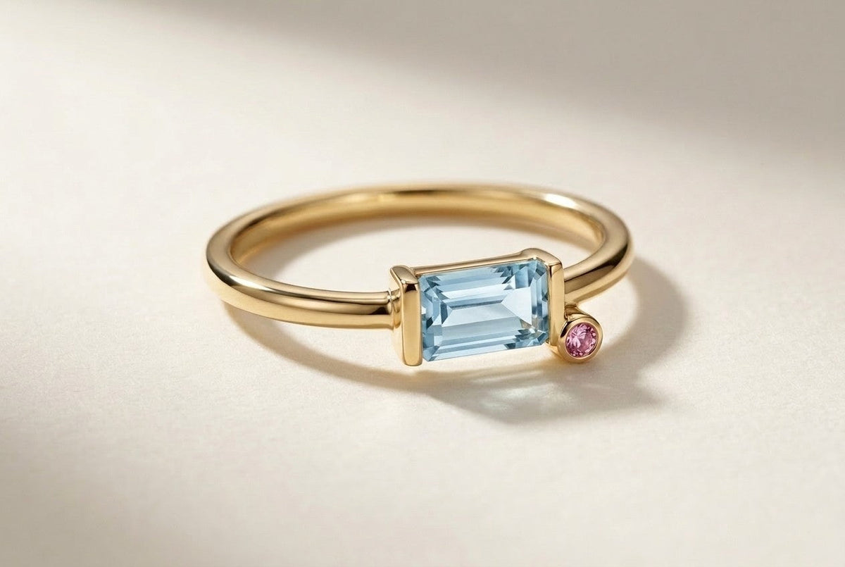 D by DONYDO Tessere Ring with pink sapphire step – emerald-cut aquamarine 8 x 4 mm in a half bezel and a 2 mm pink sapphire on a small step, slim yellow gold band | DONYDO Jewelry