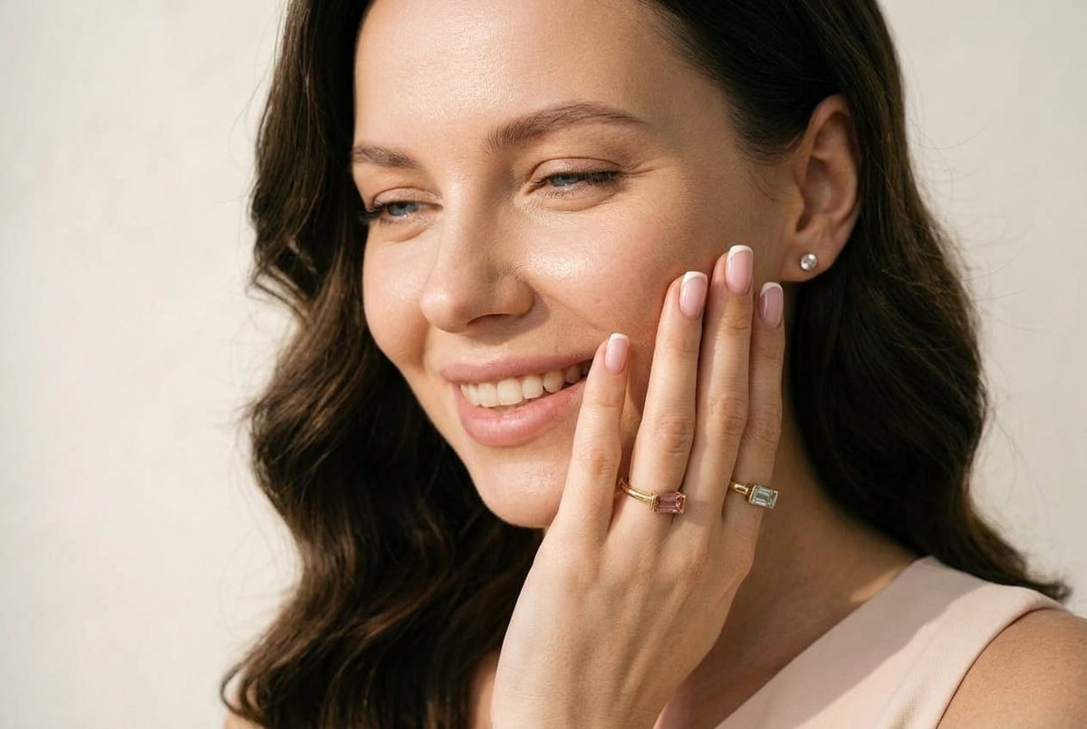 Close-up of the D by DONYDO Tessere stackable rings worn together – pink tourmaline and aquamarine in 14K yellow gold, French manicure | DONYDO Jewelry